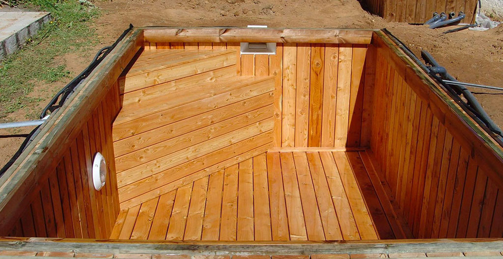 Coupe technique montrant les couches de préparation terrain pour piscine bois